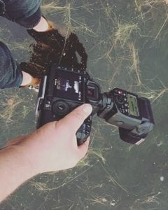 A person advertising on Facebook while capturing underwater shots with a camera.