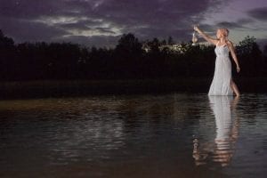 Advertisement featuring a woman in a white dress standing in water during nighttime.