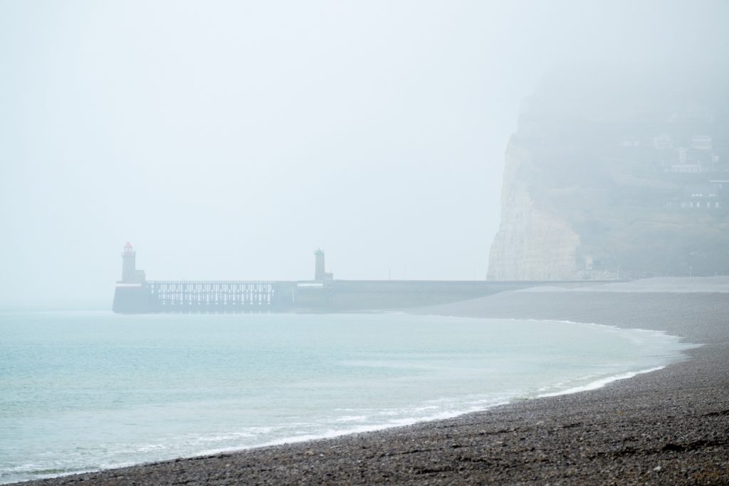 The points of interest (the lighthouse and the cliffs) are not placed smack in the middle, but in the thirds of the frame. The curved line of the shore serves as a leading line towards the subjects, leading the viewer's eye into the composition.