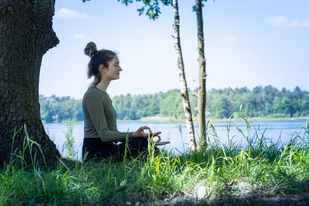 Young woman practicing mindfulness near a lake.