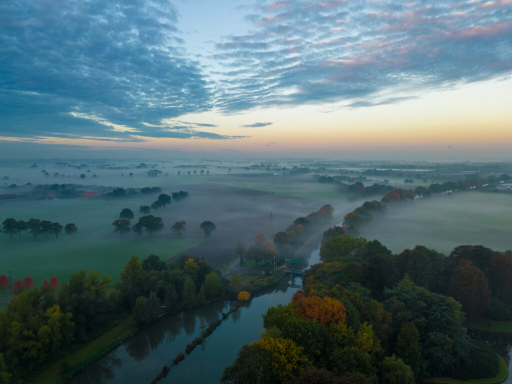 An aerial view of a foggy landscape with trees, captured using a DJI Air 3 drone.
