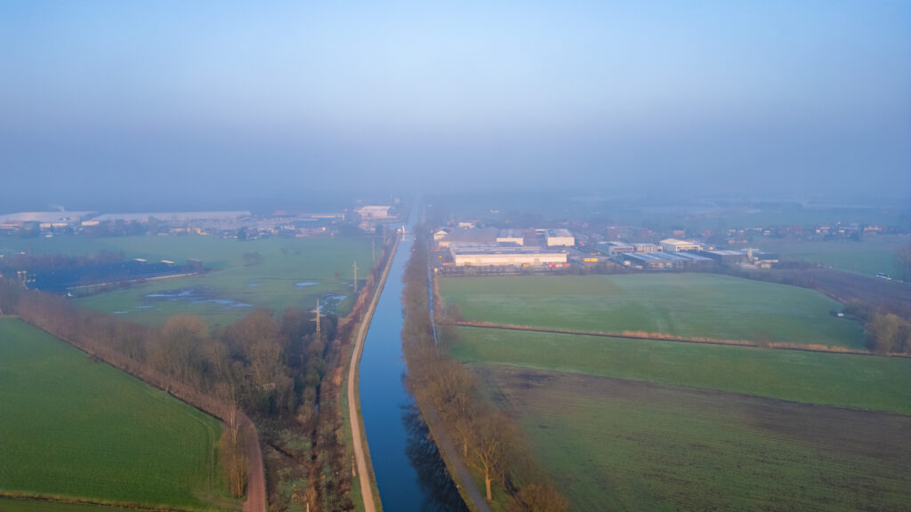 Aerial view of an industrial area beside a river on a foggy day.
